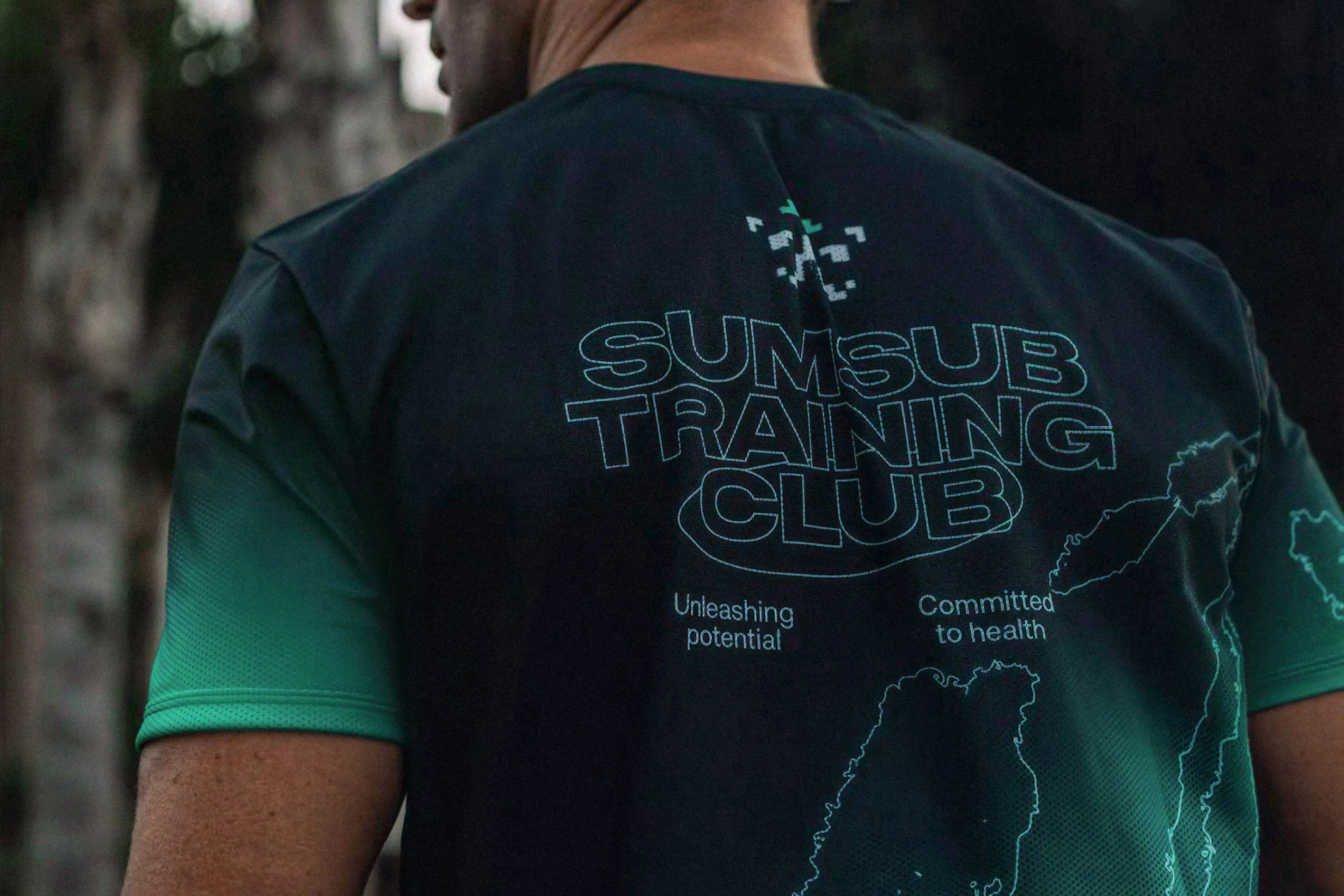 Back of a dark green-to-black T-shirt printed "Sumsub Training Club" with a small pixel logo