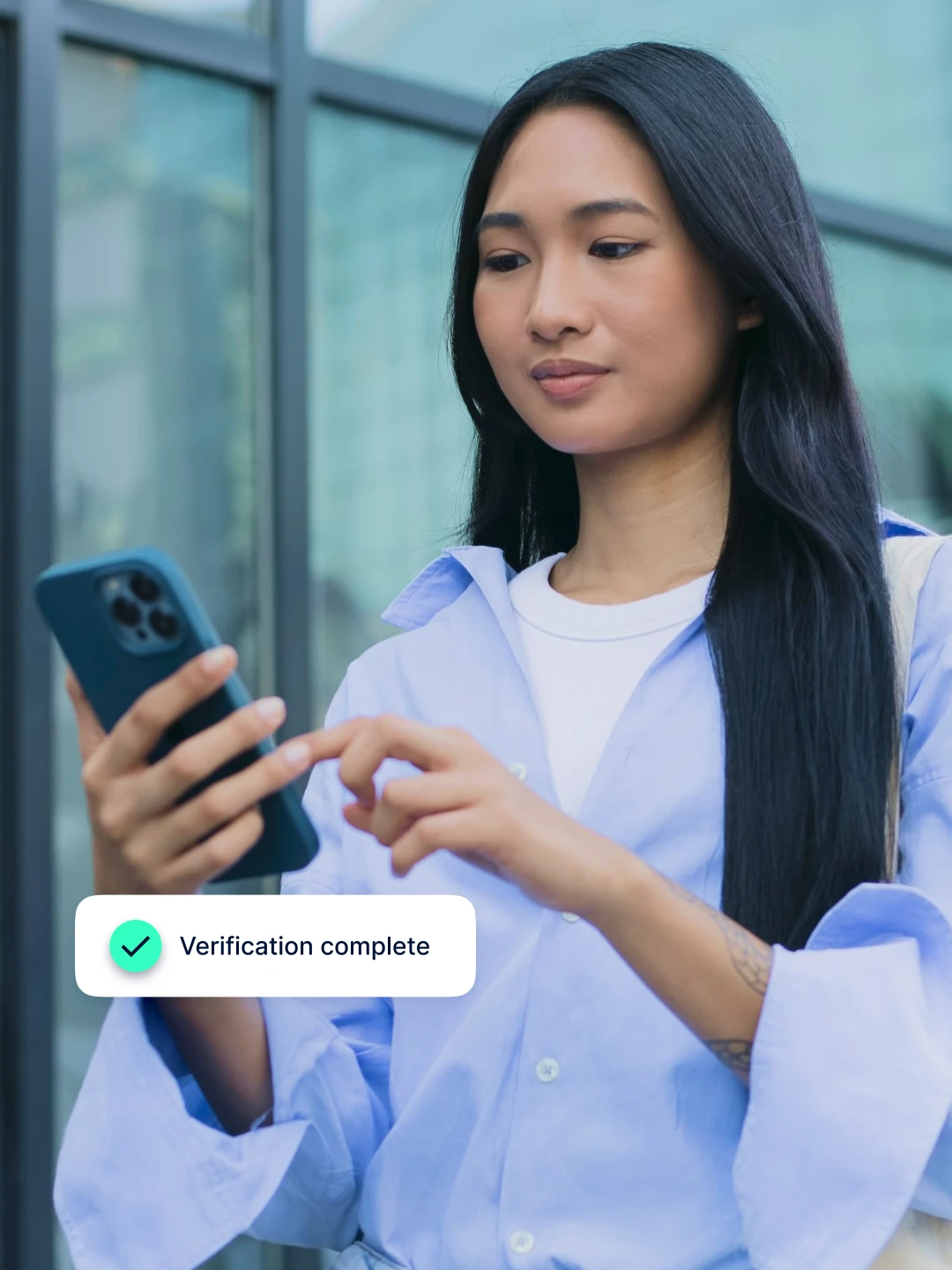 Woman in a blue shirt holding a phone, with a "Verification complete" notification at the bottom