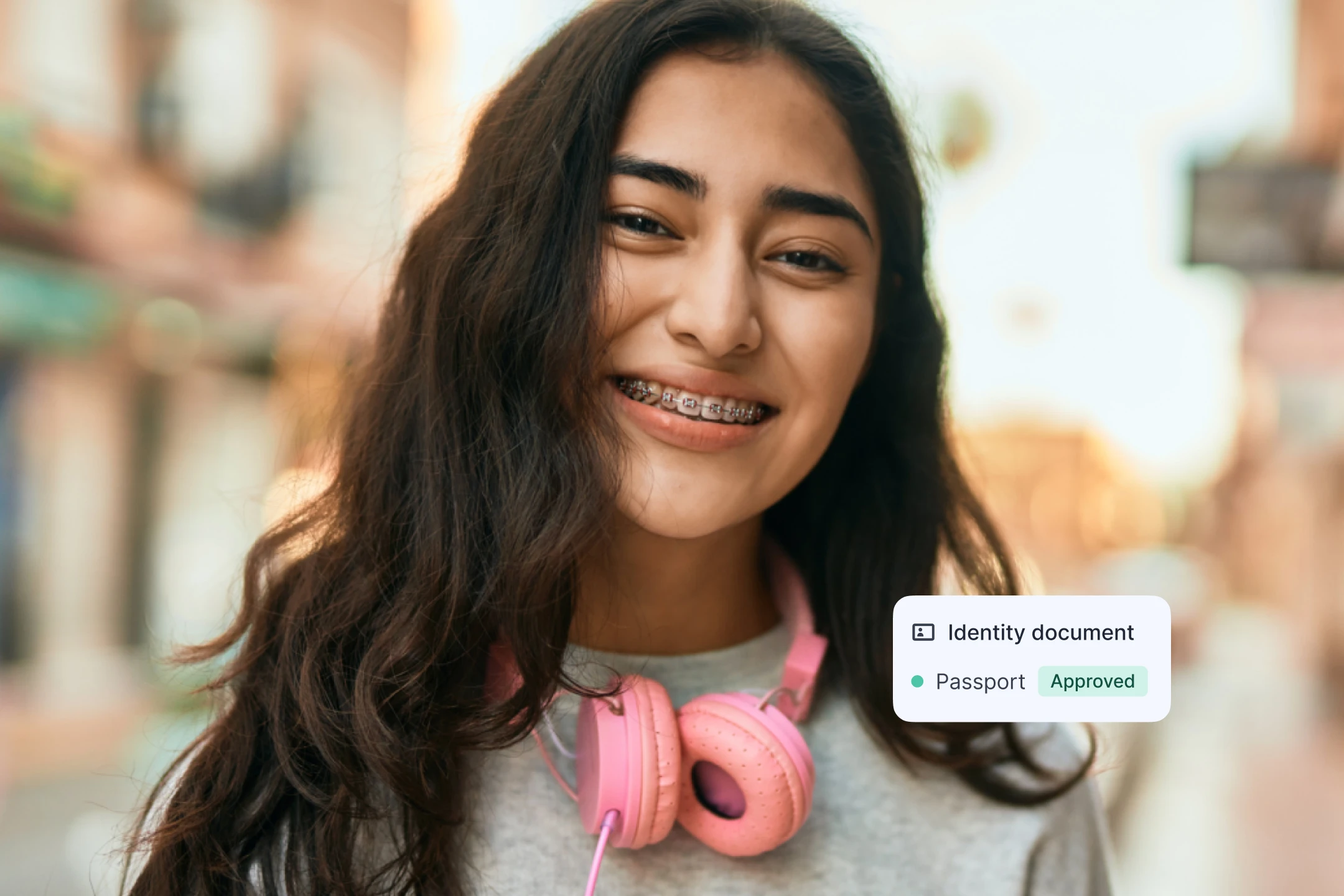 Smiling young woman with braces and pink headphones, with an "Identity document—Passport—Approved" interface tag